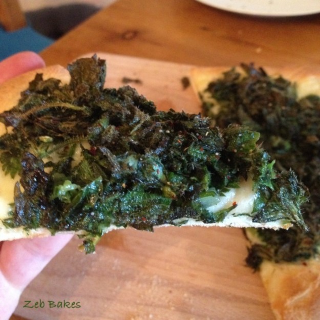 A slice of pizza topped with tender and subdued nettles
